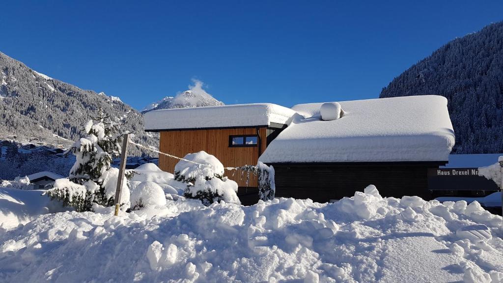 a building covered in snow with a pile of snow at Haus Idili in Sankt Gallenkirch