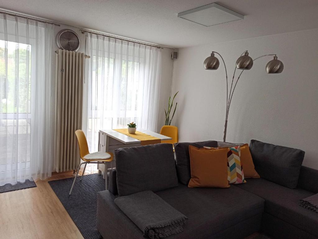 ein Wohnzimmer mit einem grauen Sofa und einem Tisch in der Unterkunft Fewo Höhbergblick in Tauberbischofsheim