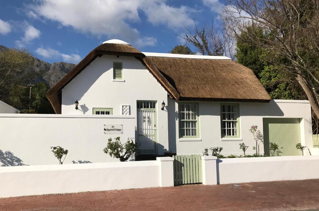 a white house with a thatched roof at Squirrel Cottage in Franschhoek