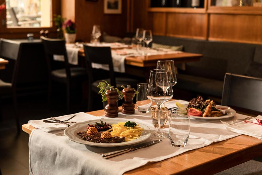 a table with two plates of food and wine glasses at Hotel Engelberg "mein Trail Hotel" in Engelberg