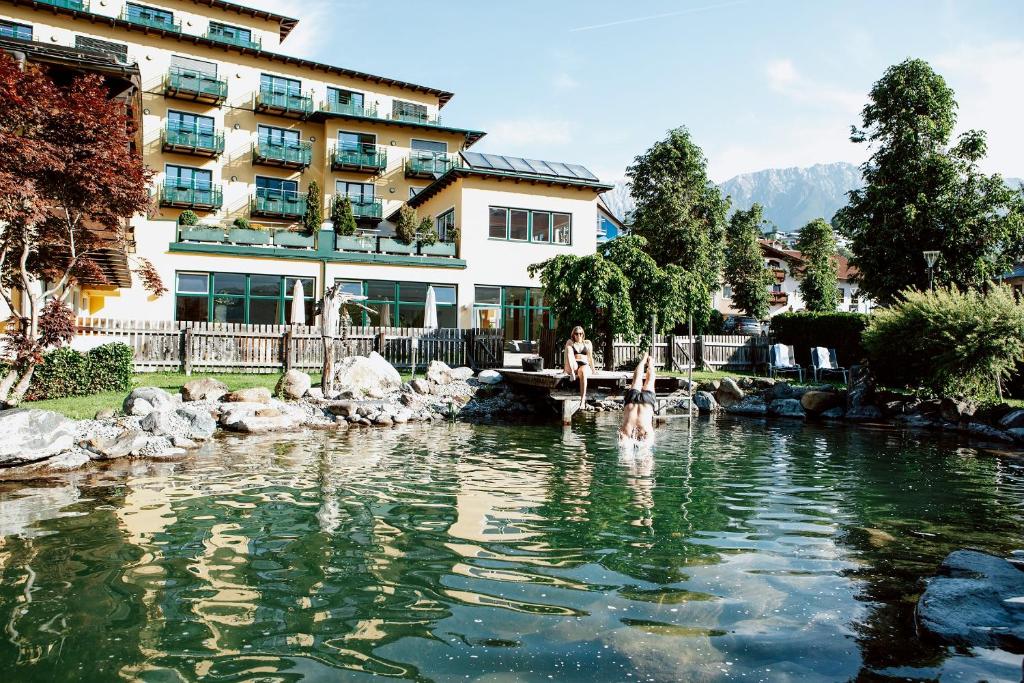 Una donna in piedi in uno stagno di fronte a un edificio di Hotel Zum Hirschen a Imst