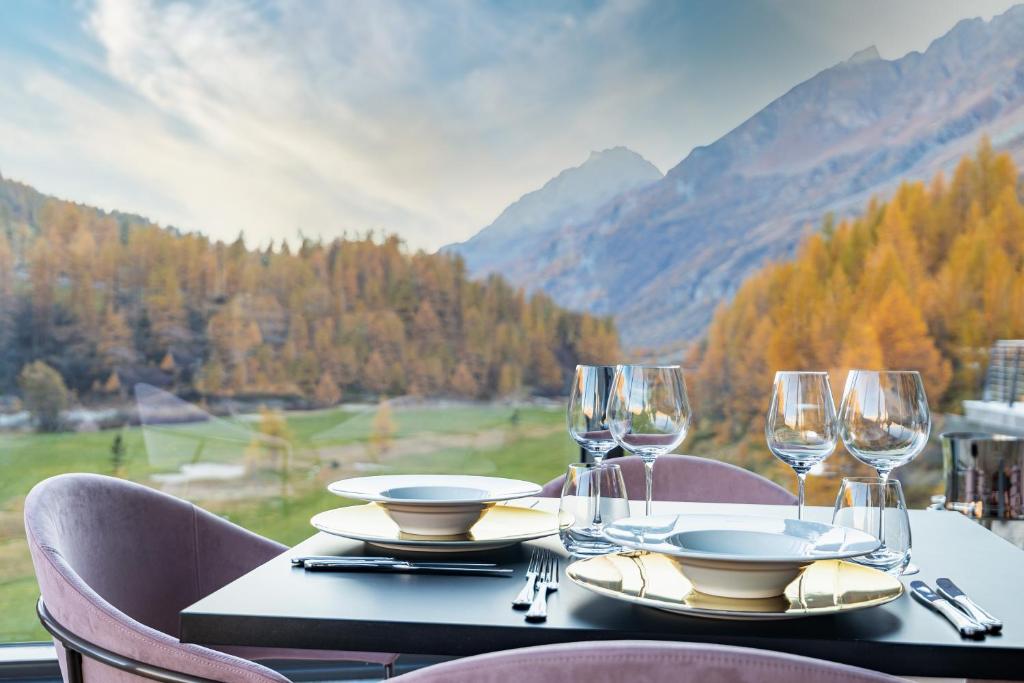 a table with glasses and plates on a table with a view at Cervino - VRetreats in Breuil-Cervinia
