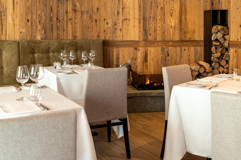 a restaurant with white tables and chairs with wine glasses at Cervino - VRetreats in Breuil-Cervinia