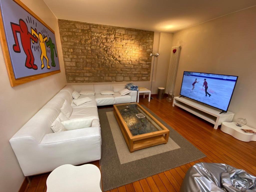 Ca' Mancio في فابريانو: غرفة معيشة مع أريكة بيضاء وتلفزيون بشاشة مسطحة
