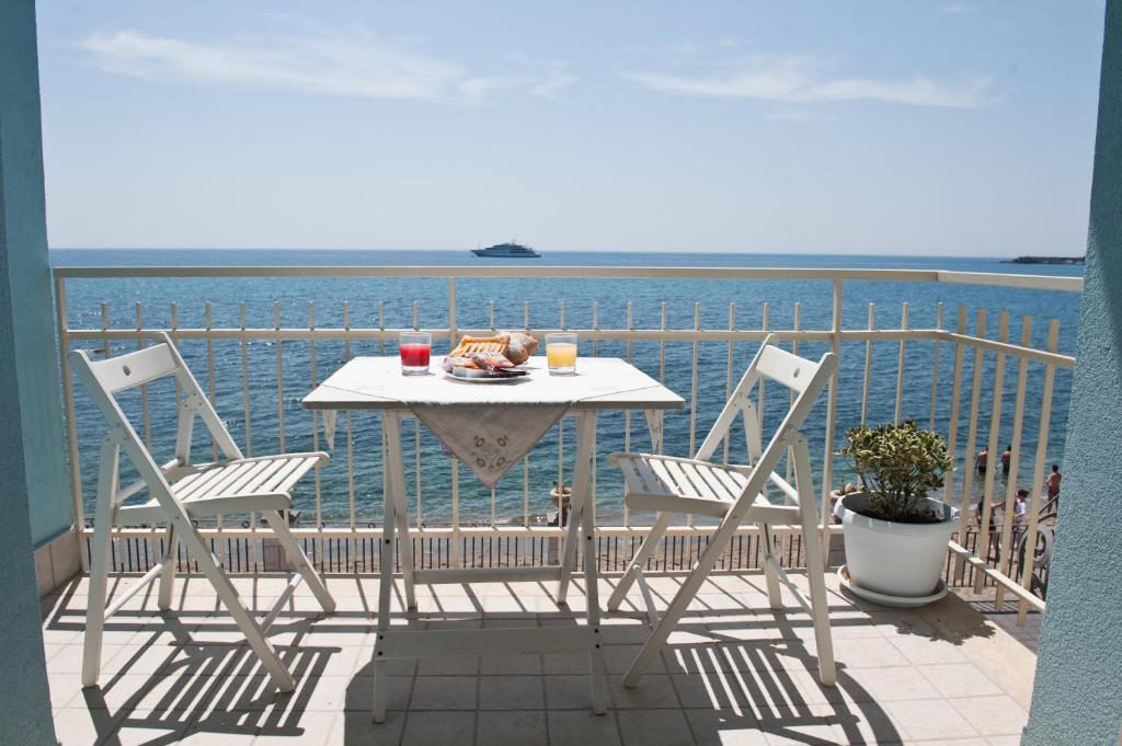 een tafel en stoelen op een balkon met uitzicht op de oceaan bij Nina B&B in Giardini Naxos