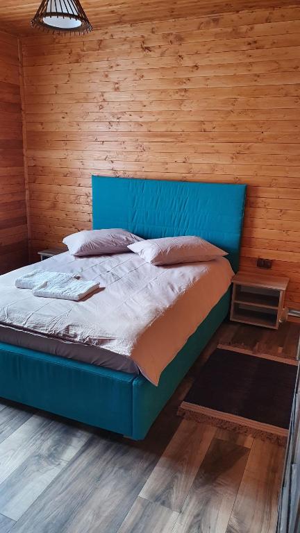 Cama azul en habitación con pared de madera en Cabana Deliuta en Cavnic