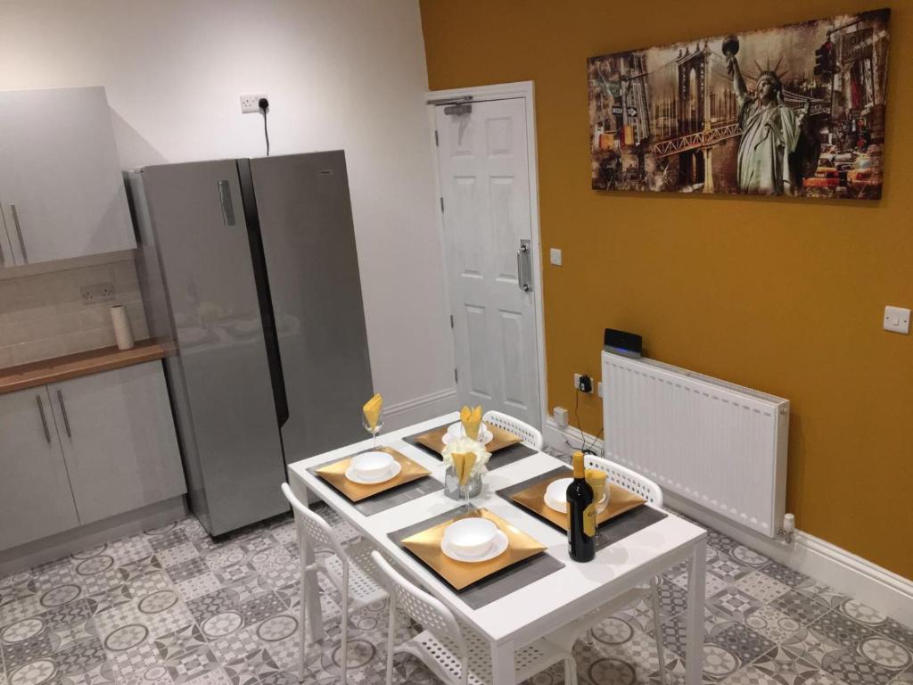 a kitchen with a table with two chairs and a refrigerator at Townhouse @ 46 Nelson Street Crewe in Crewe