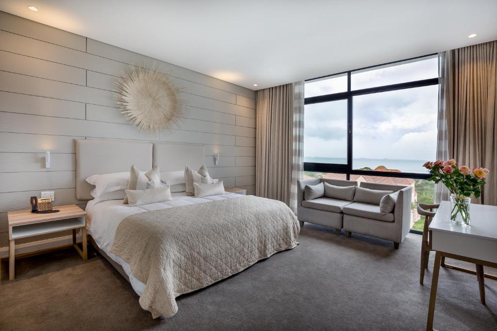 ein Schlafzimmer mit einem Bett, einem Stuhl und einem Fenster in der Unterkunft Bluewater Bay Sunrise Hotel in Amsterdamhoek