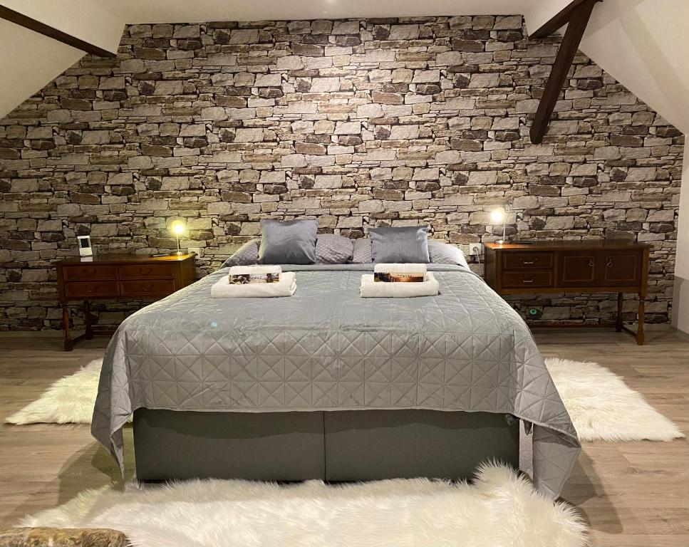 a bedroom with a large bed with a brick wall at SG chalupa MLÁZOVICE - WELLNESS v ceně in Mlázovice