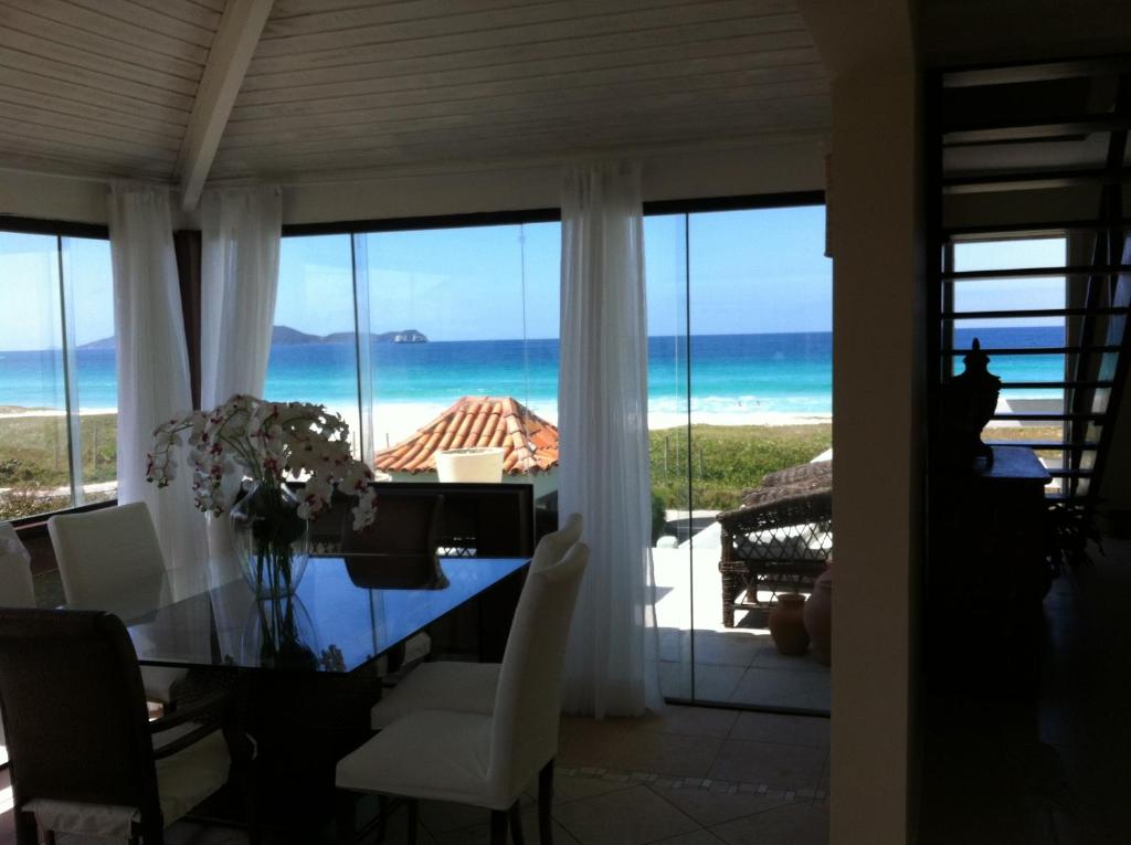 a dining room with a table and a view of the ocean at Casa Pé na Areia Cabo Frio in Cabo Frio