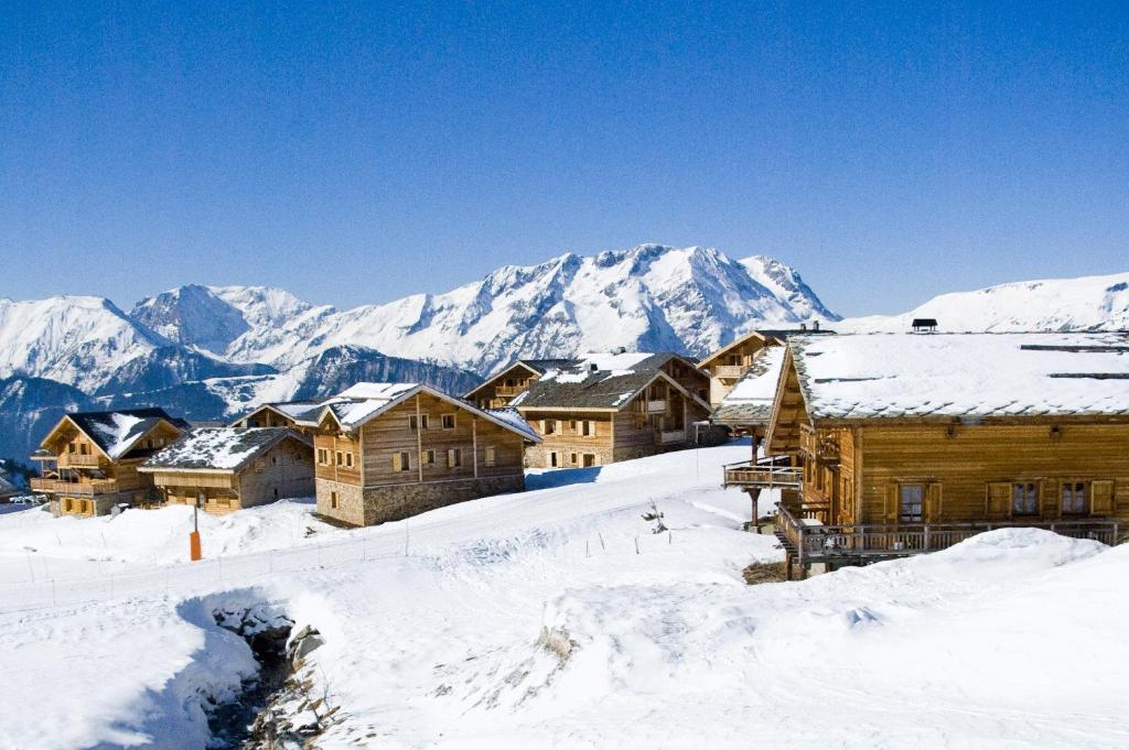 a group of buildings in the snow with mountains at Madame Vacances Les Chalets de l'Altiport in L'Alpe-d'Huez