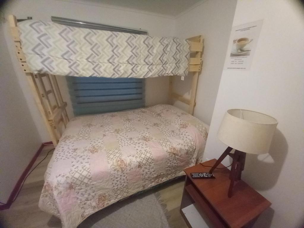 Dormitorio pequeño con cama y lámpara en Hostal Brisas del Sur en Puerto Varas