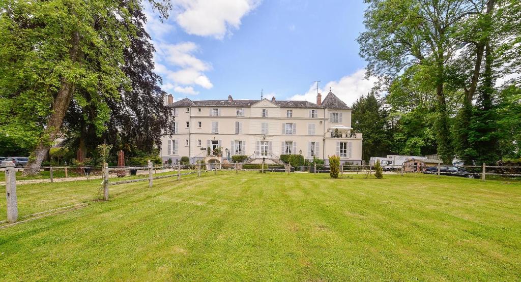 une grande maison blanche avec une grande pelouse dans l'établissement Hôtellerie Nouvelle de Villemartin, à Morigny-Champigny