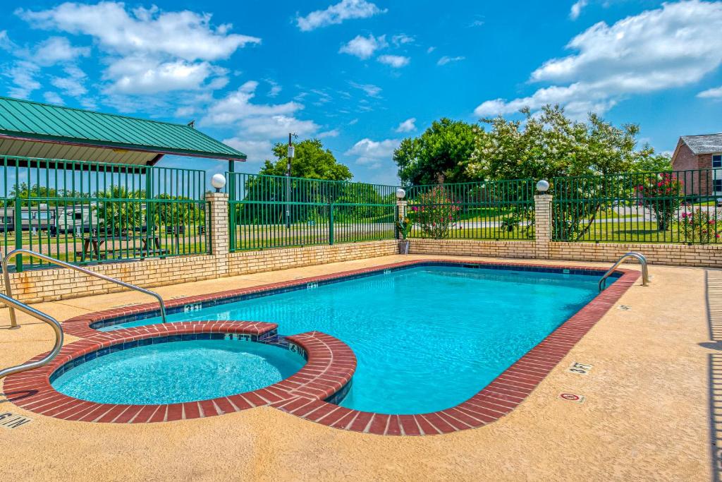 a swimming pool in a yard with a fence at OYO Hotel Yoakum West in Yoakum