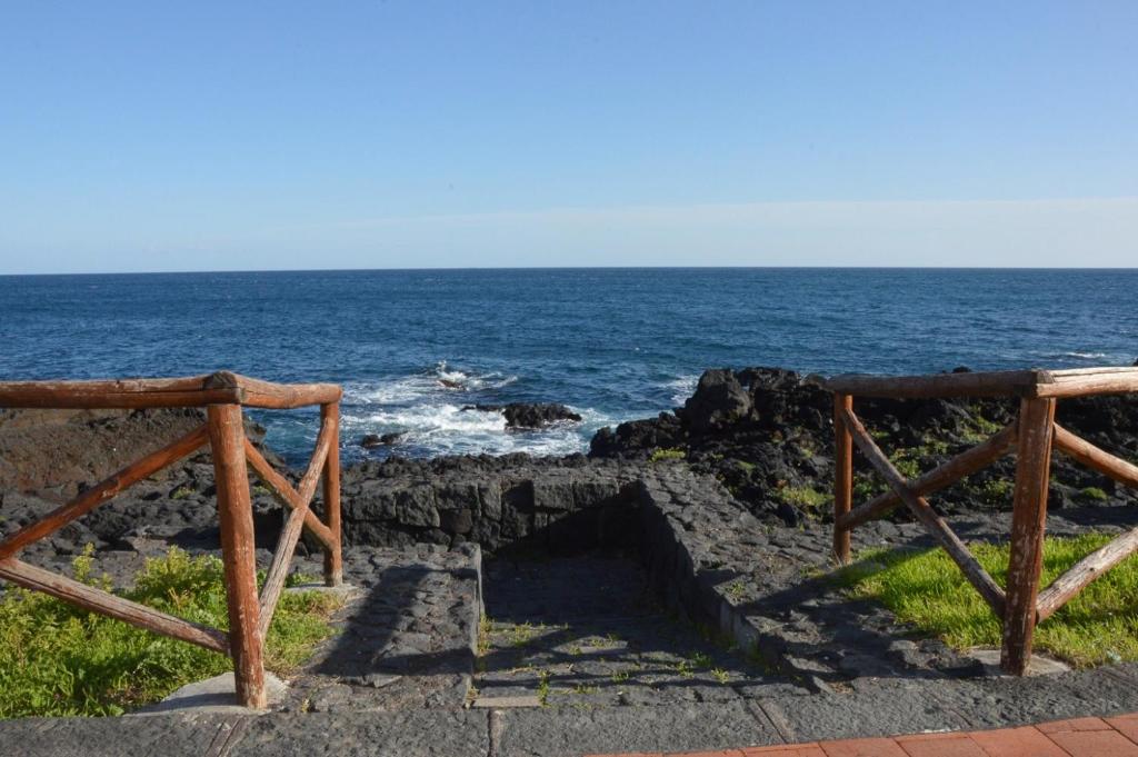 a view of the ocean with two wooden fences at Appartamento le calette in Stazzo