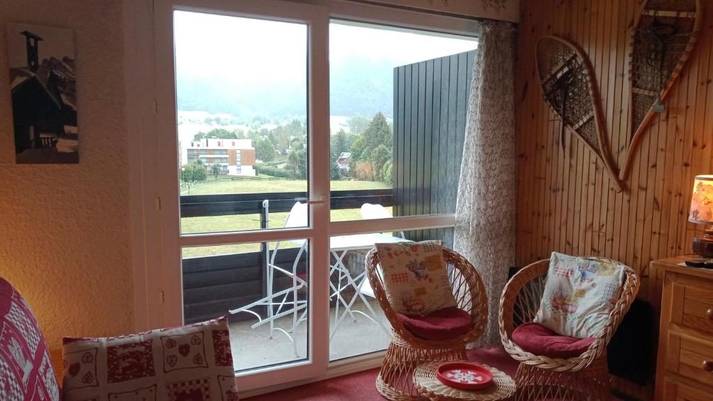 a room with chairs and a window with a view of a balcony at le Vercors en toute simplicite in Autrans