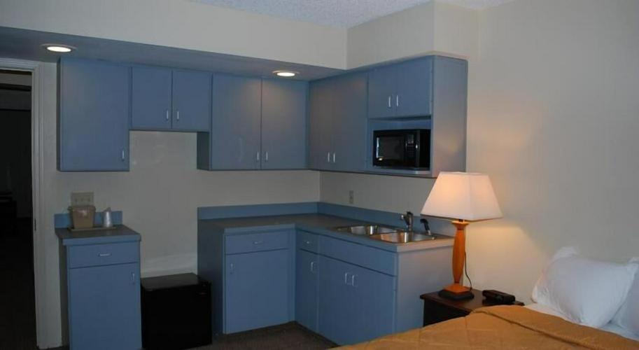 a kitchen with blue cabinets and a bed and a lamp at Clinton Inn & Suites in Port Clinton