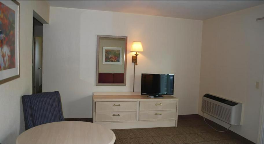 a room with a table and a tv on a dresser at Clinton Inn & Suites in Port Clinton