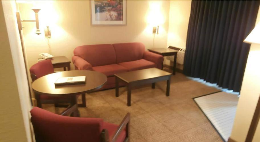 a living room with a couch and tables in a hotel room at Clinton Inn & Suites in Port Clinton