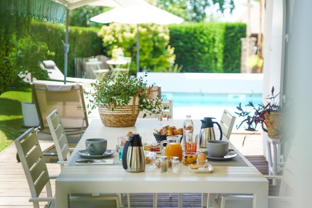 Biały stół z jedzeniem na patio w obiekcie Chambres d'hôtes Villa Surcouf w mieście Andernos-les-Bains