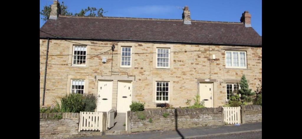 una casa de ladrillo con puertas blancas y una valla en Listed sword makers cottage in Shotley Bridge en Consett