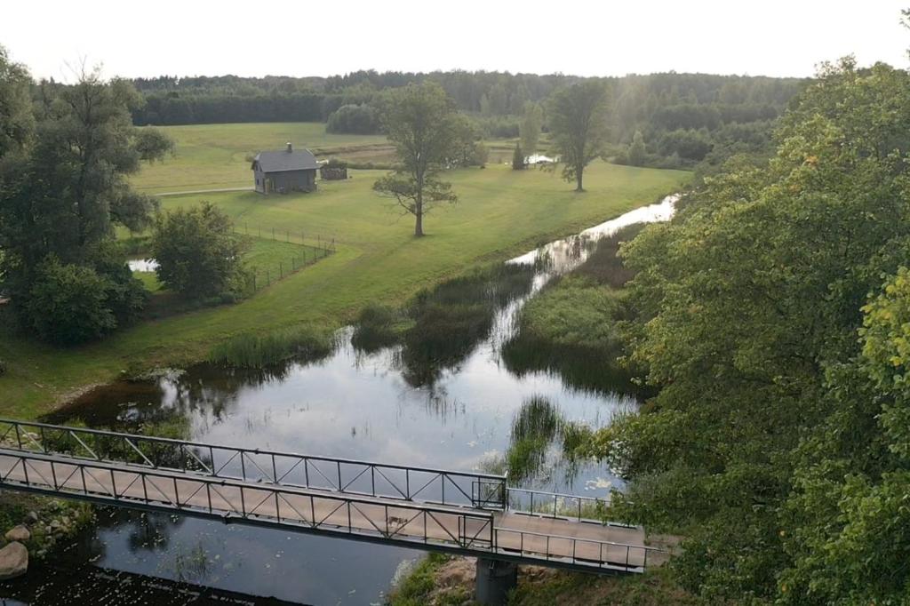 uma ponte sobre um rio com uma casa à distância em Stadelnieki em Stadelnieki