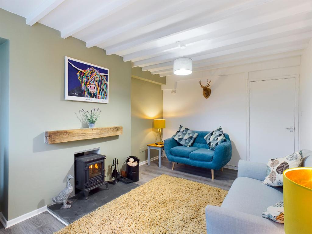 uma sala de estar com um sofá azul e uma lareira em welsh country cottage in beautiful village em Llandudno Junction