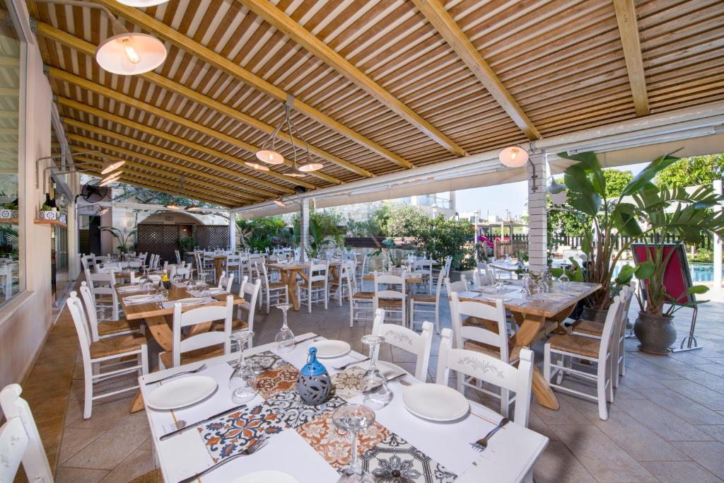 a restaurant with white tables and white chairs at Isida Hotel Agia Marina in Agia Marina Nea Kydonias