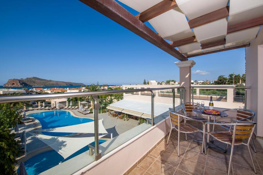 a balcony with a table and chairs and a view of the pool at Isida Hotel Agia Marina in Agia Marina Nea Kydonias