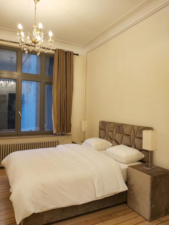 Un dormitorio con una gran cama blanca y una ventana en Brussels 1904, en Bruselas