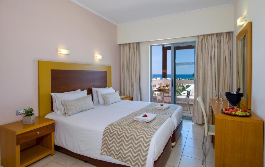 a bedroom with a large bed and a balcony at Isida Hotel Agia Marina in Agia Marina Nea Kydonias