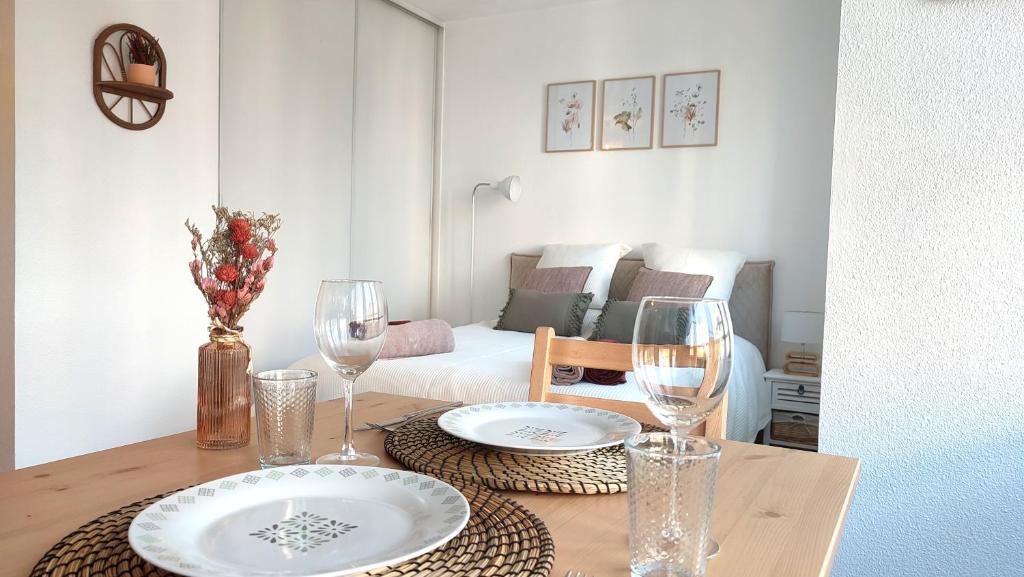 - une table avec deux assiettes et des verres à vin dans l'établissement Joli Studio Tout Confort - Centre-ville, à Annecy