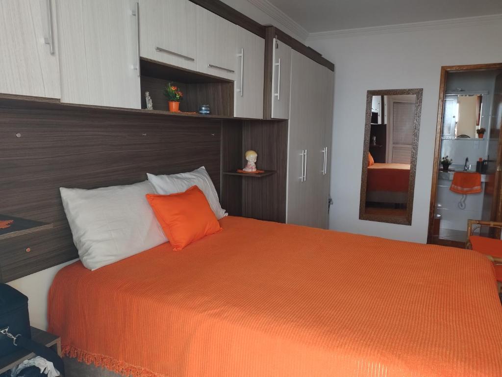 1 dormitorio con cama de color naranja y almohada de color naranja en Apartamento na Praia Grande en Praia Grande