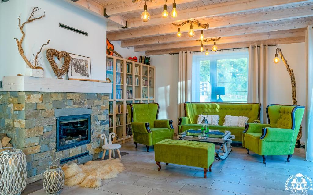 a living room with green chairs and a stone fireplace at Agroturystyka Corno Owca in Żabnica