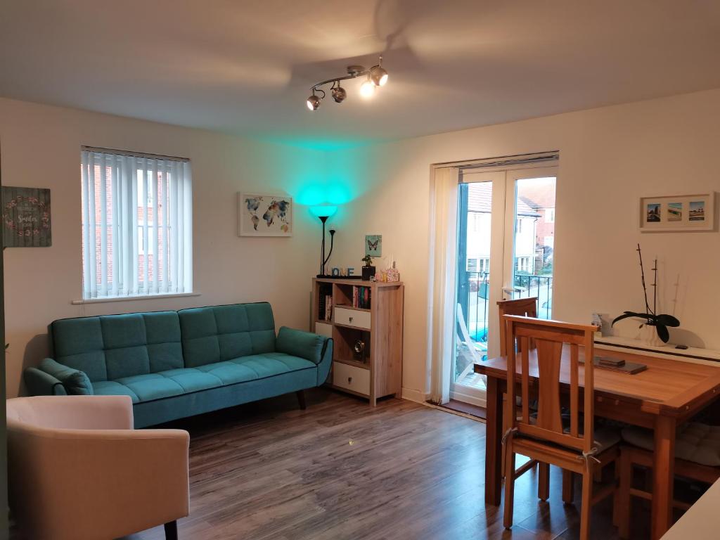 Cosy Apartment with Balcony في هيرن باي: غرفة معيشة مع أريكة خضراء وطاولة