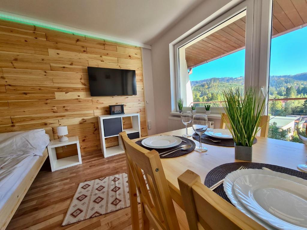 een eetkamer met een tafel en een groot raam bij Apartamenty Willa NaSkarpie Jacuzzi Sauna Basen in Wisła