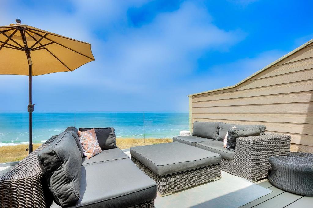 een patio met een bank, stoelen en een parasol bij Encinitas Seabluffe Oceanfront Condo in Encinitas