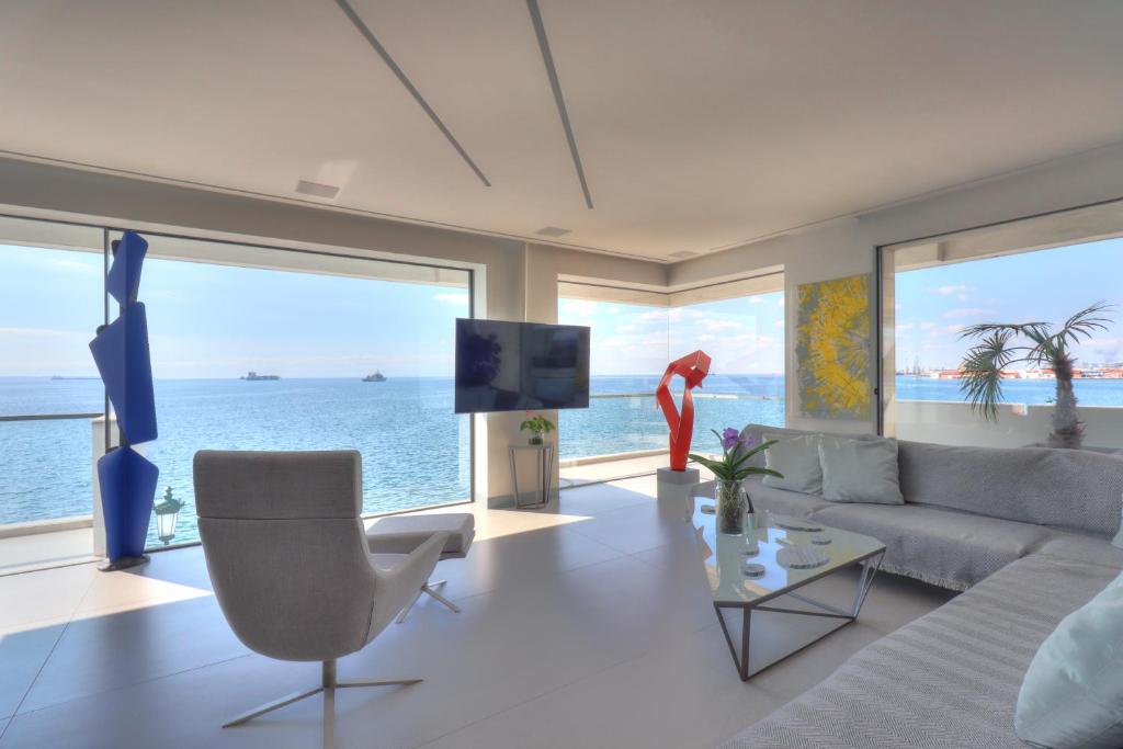 a living room with a couch and a tv and the ocean at Infinity Sea View Apartment in Thessaloniki