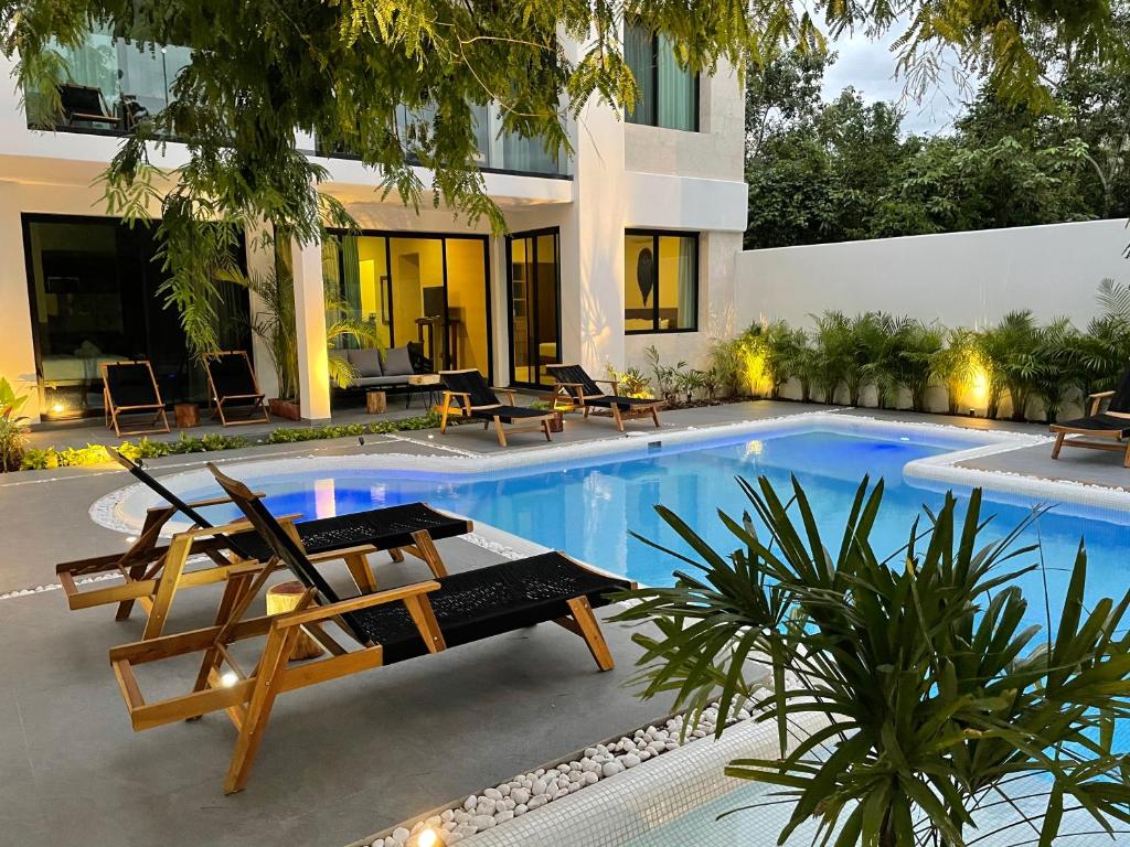 a swimming pool with two lounge chairs next to a building at The Reserve Tulum in Tulum