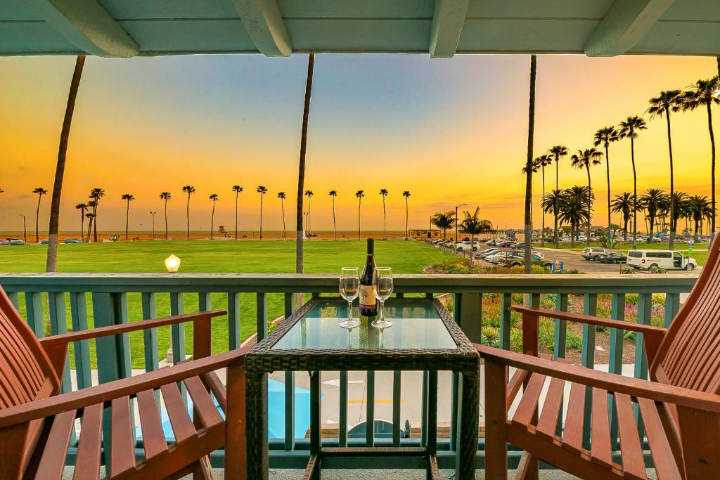 a table with wine glasses on a balcony with palm trees at Groundswell 4 Bedroom in Newport Beach