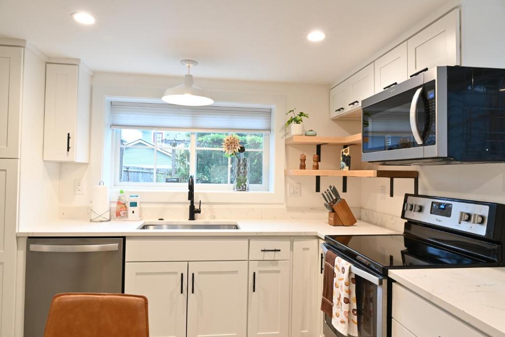 a kitchen with white cabinets and a sink and a window at Modern and warm house in Seattle