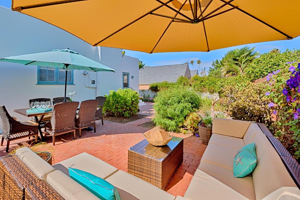 un patio con sofá y sombrilla en Seashell Cottage, en San Diego