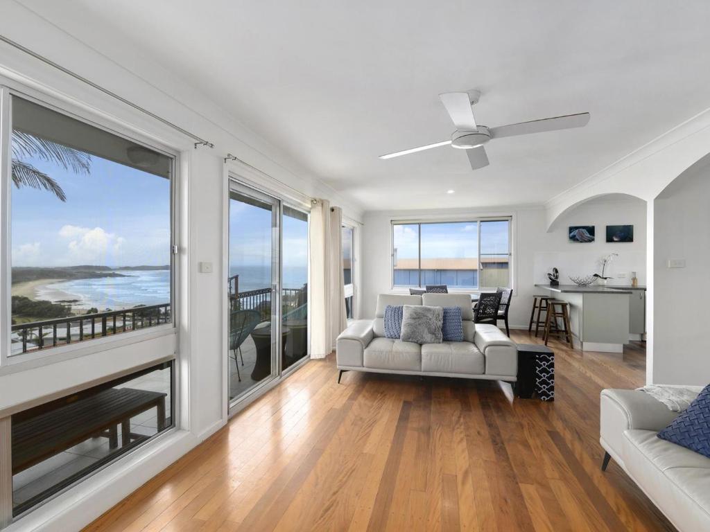 a living room with a couch and large windows at Emerald Views Signal Street 9 in Emerald Beach