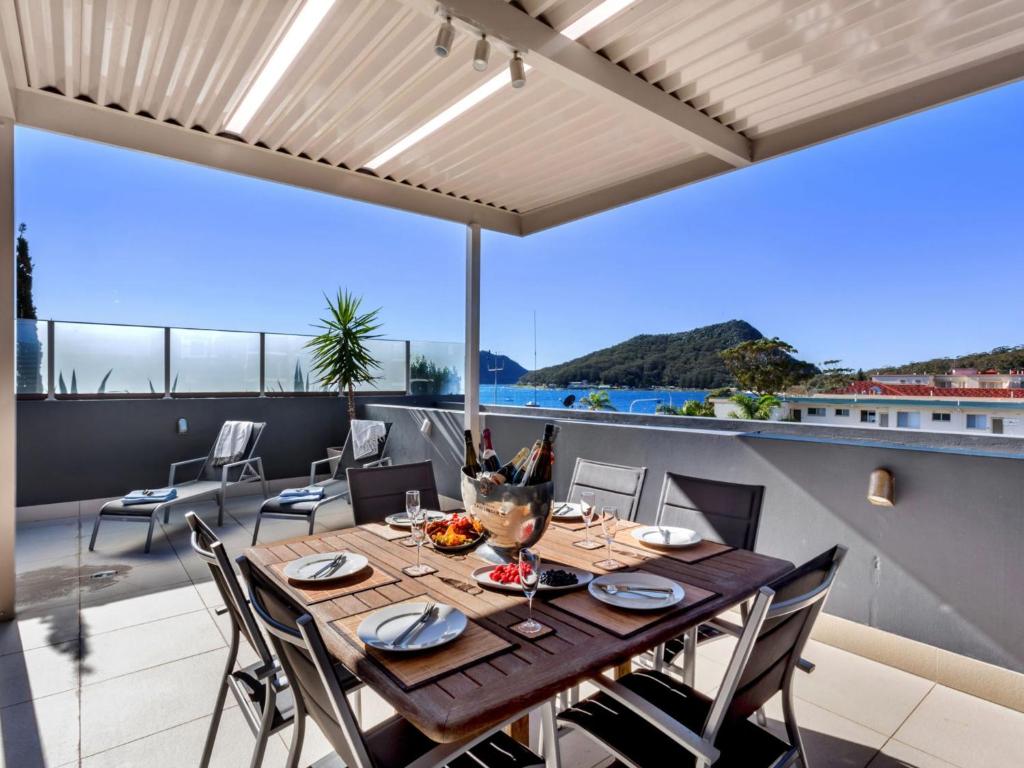 a dining room with a table and chairs on a balcony at Aura Apartments Unit 13 59 Shoal Bay Road in Shoal Bay