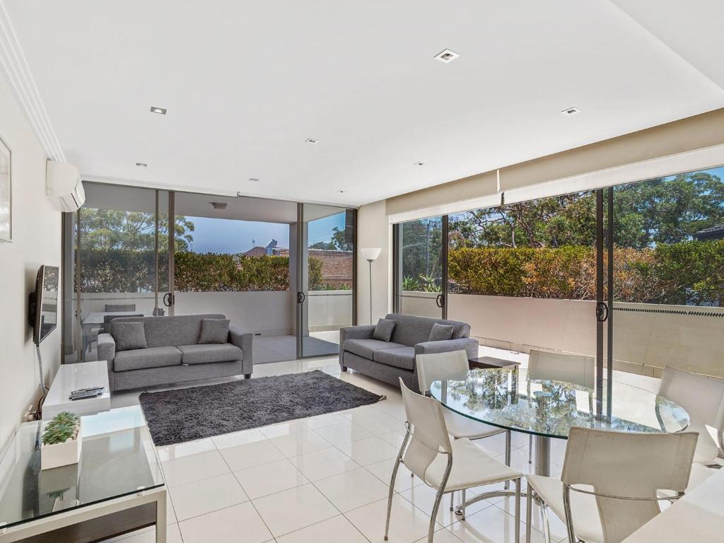 a living room with a glass table and chairs at Aura Apartments Unit 5 59 Shoal Bay Road in Shoal Bay