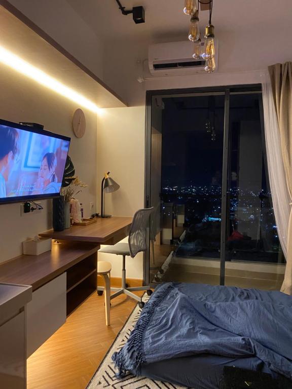 Skyhouse Bsd warm and cozy studio by lalerooms في تانغيرانغ: غرفة نوم مع سرير ومكتب مع نافذة كبيرة