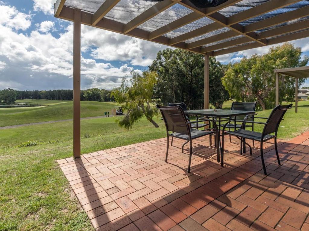 a patio with a table and chairs under a pergola at Horizons Golf Club Villa 124 in Salamander Bay