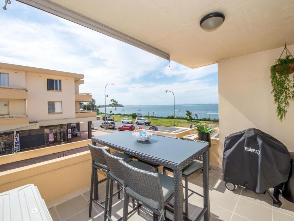 a balcony with a table and chairs and a view of a street at Bay Village Unit 2 47 Shoal Bay Road in Shoal Bay