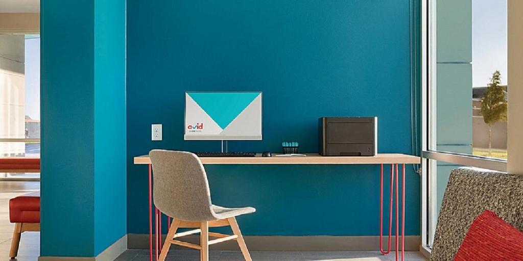 a desk with a chair and a computer on it at avid hotels - Zeeland by IHG in Holland