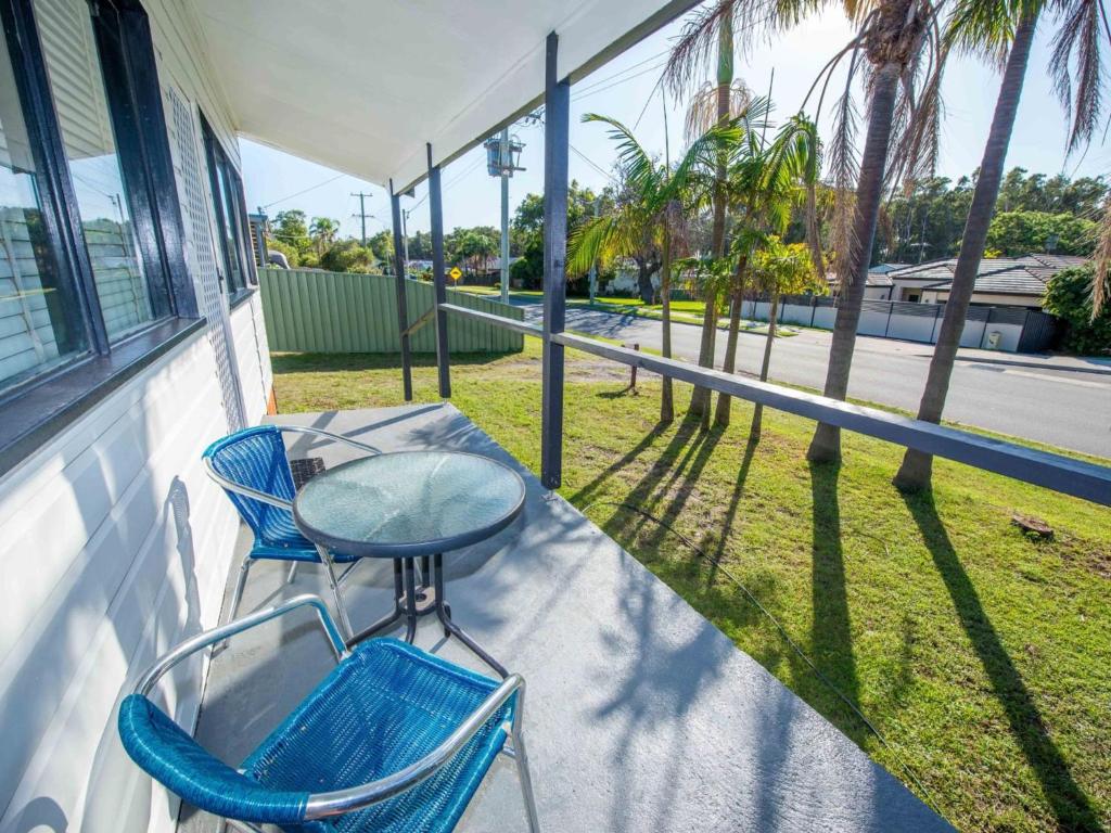 a porch with two chairs and a table and a street at Beach House on James Patterson in Anna Bay